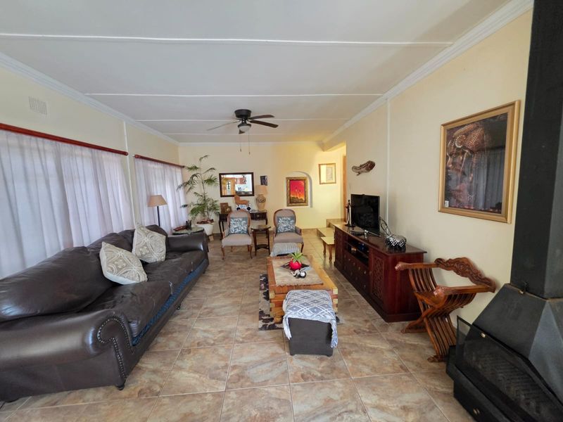 Spacious living room featuring tiled flooring, a ceiling fan, and a built-in fireplace, offering a comfortable and functional family living space.