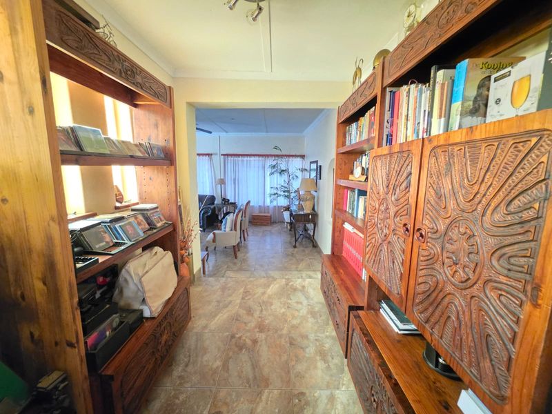 A tiled hallway connecting to an adjacent living area, featuring neutral wall finishes and overhead lighting.