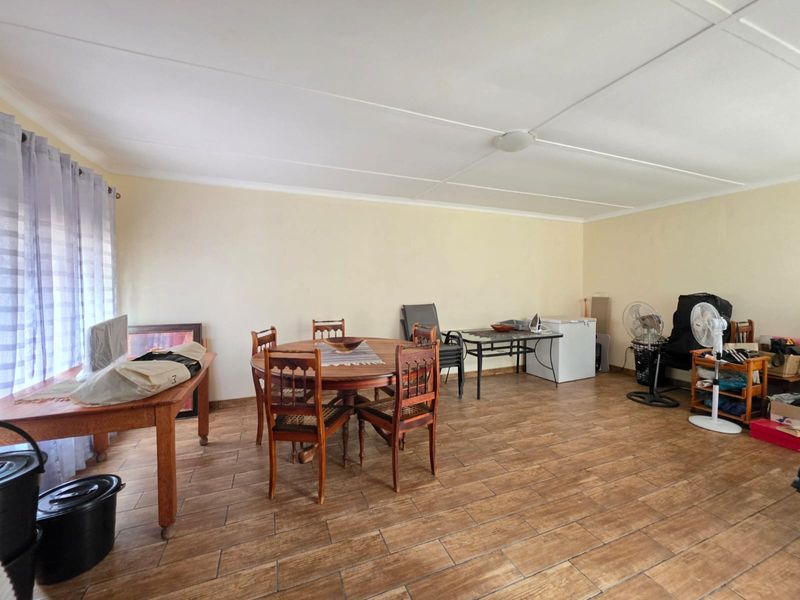 A spacious dining area featuring wood-look ceramic floor tiles and a neutral wall finish, offering a versatile layout for family meals.