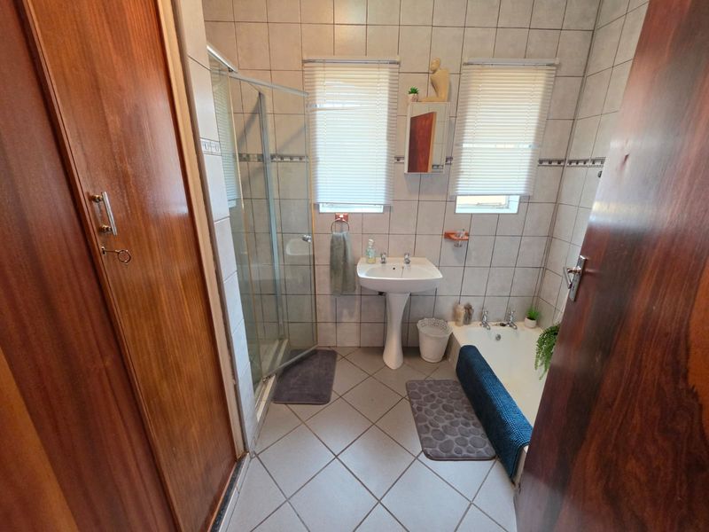 A functional bathroom featuring a pedestal basin, a separate shower enclosure, a bathtub, and tiled finishes throughout.