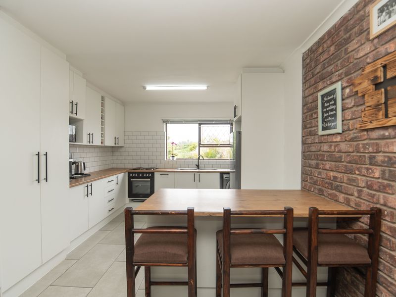 Modern kitchen featuring white cabinetry, subway tile backsplash, built-in oven, and a unique exposed brick feature wall with an integrated breakfast bar.