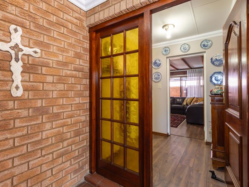 Entrance foyer featuring exposed brickwork, timber sliding door with decorative glass panels, and laminate flooring leading into the main living area.