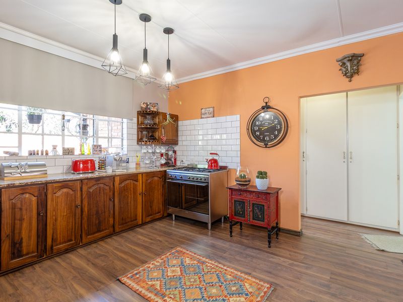 A functional kitchen featuring wooden cabinetry, granite countertops, subway tile backsplash, and a freestanding gas stove with modern pendant lighting.