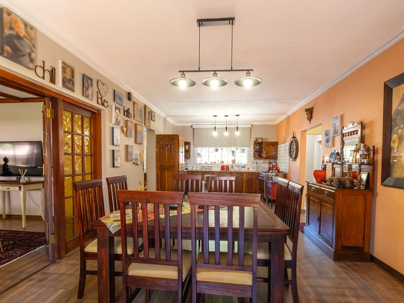 Open plan dining and kitchen area featuring laminate flooring, timber cabinetry, and decorative pendant lighting, creating a warm and functional living space.