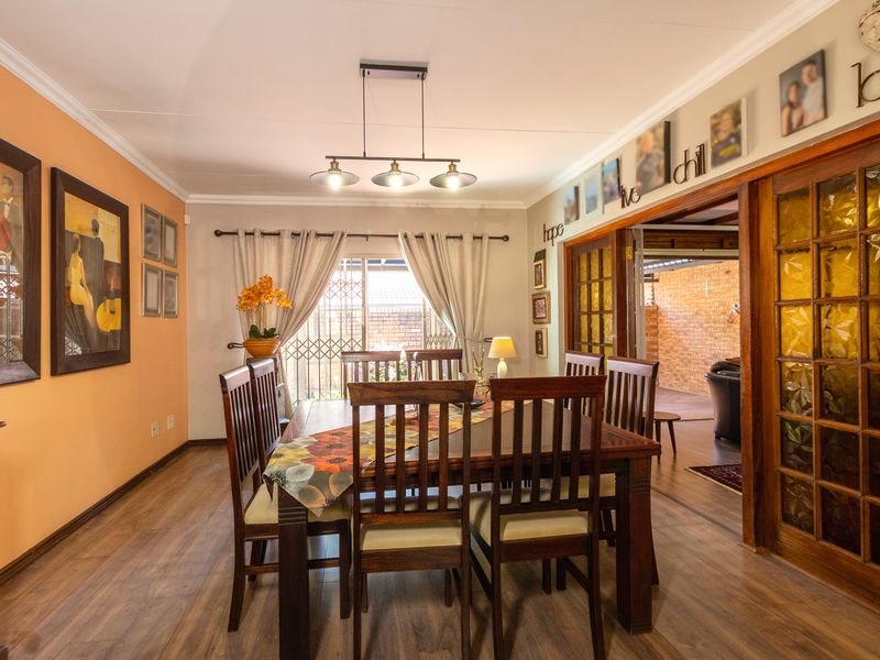 A well-maintained dining room featuring laminate flooring, pendant lighting, and sliding glass doors that provide access to the adjacent living area.