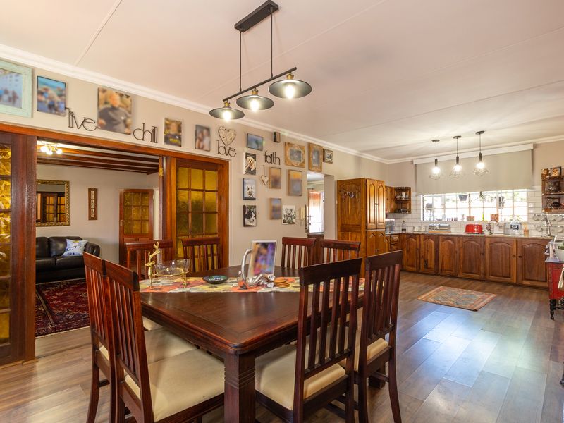 Spacious open-plan dining and kitchen area featuring warm wooden cabinetry, laminate flooring, and classic pendant lighting, connecting seamlessly to the adjacent living room.