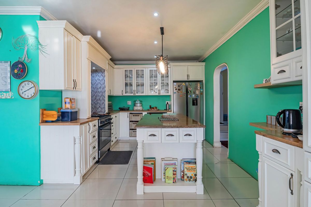 Spacious kitchen featuring white cabinetry, granite countertops, a central island, and tiled flooring, offering a functional layout with ample storage space.