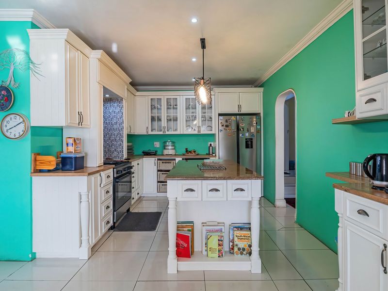 Spacious kitchen featuring white cabinetry, granite countertops, a central island, and tiled flooring, offering a functional layout with ample storage space.