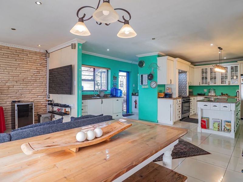 Spacious open-plan living and kitchen area featuring a stone accent wall, tiled floors, and a functional kitchen with island and built-in appliances.