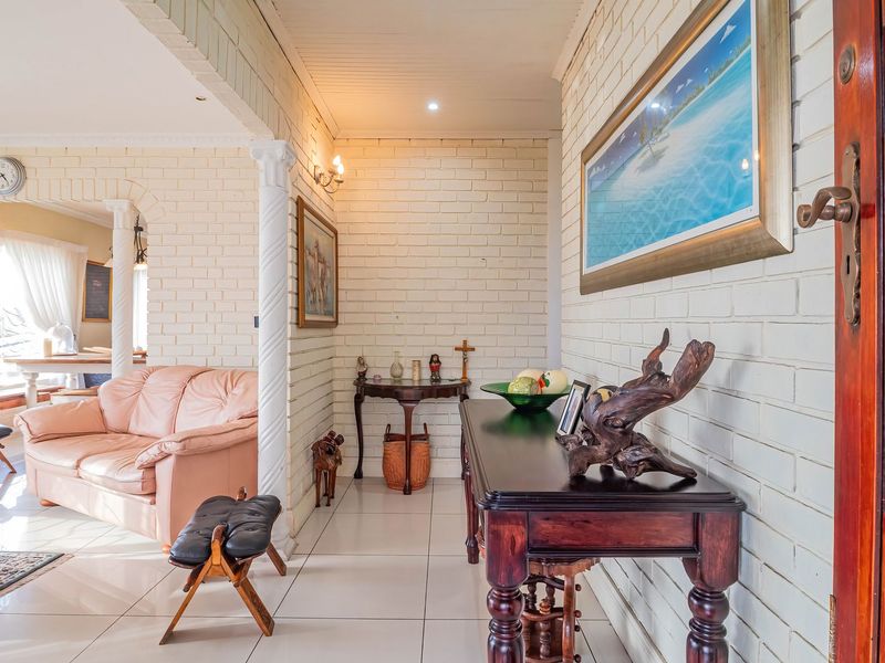 Welcoming entrance hall featuring painted brick walls, tiled flooring, and an arched transition into the adjacent living area.