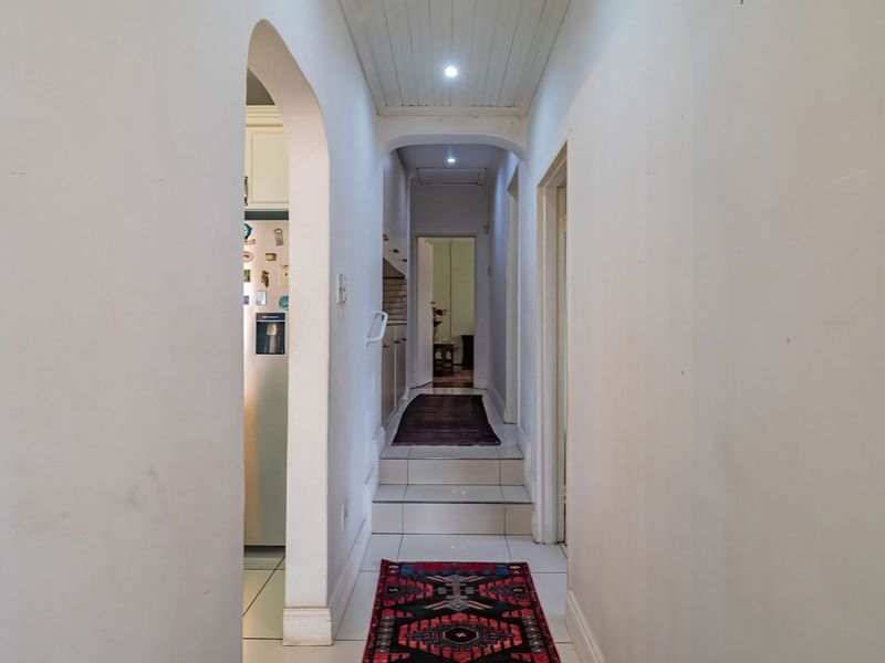 A functional hallway featuring tiled flooring, arched architectural details, and a tongue and groove ceiling with recessed lighting.