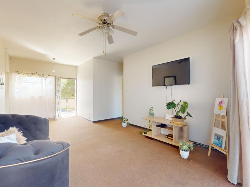 Spacious living area featuring a ceiling fan, neutral wall finishes, and direct access to an outdoor balcony space.