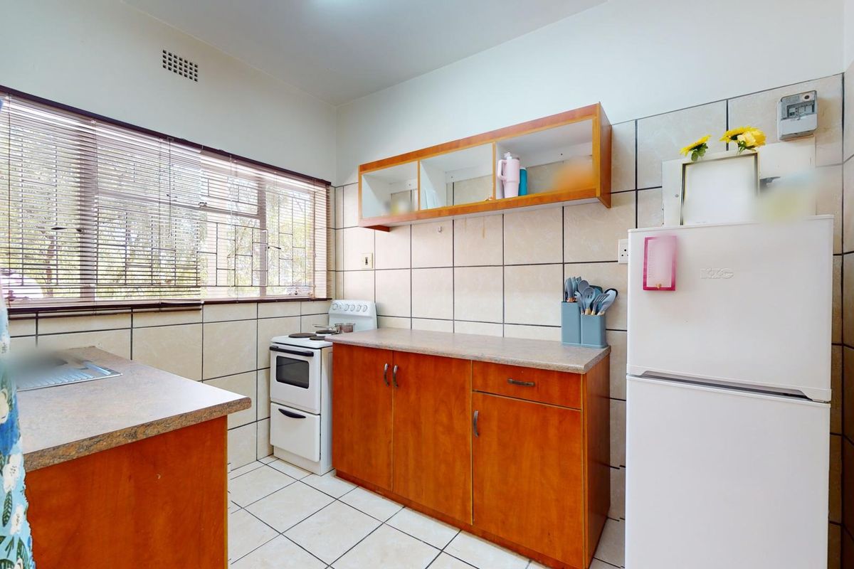 A functional kitchen featuring wooden cabinetry, tiled walls, and a freestanding stove, offering a practical layout for daily meal preparation.