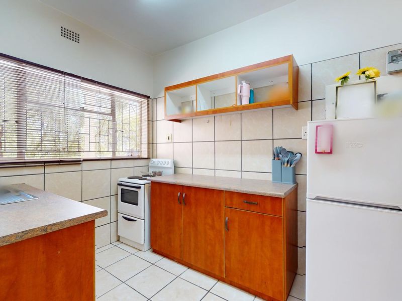 A functional kitchen featuring wooden cabinetry, tiled walls, and a freestanding stove, offering a practical layout for daily meal preparation.