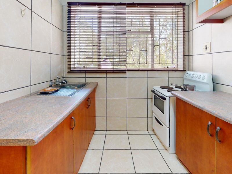 A compact, functional kitchen featuring tiled walls and floors, laminate countertops, and built-in cabinetry with a freestanding stove.