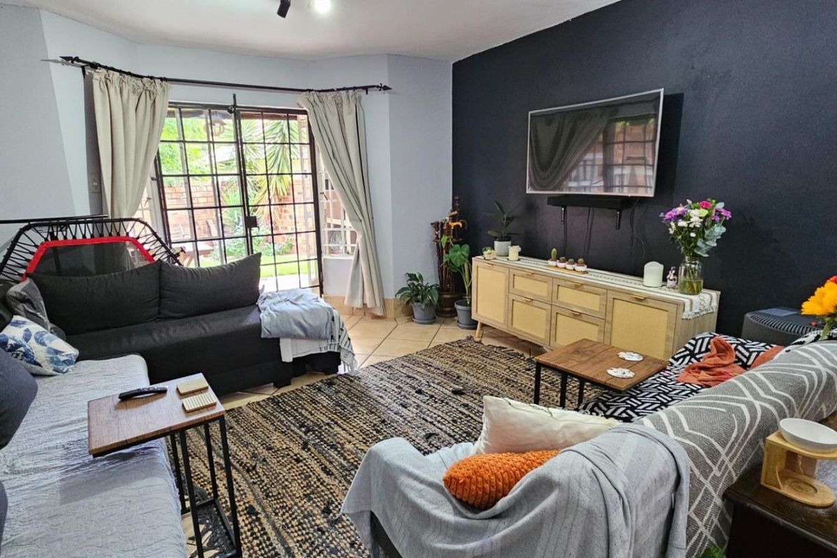 A comfortable living room featuring tiled flooring, a dark accent wall, and a sliding glass door providing access to the outdoor area.