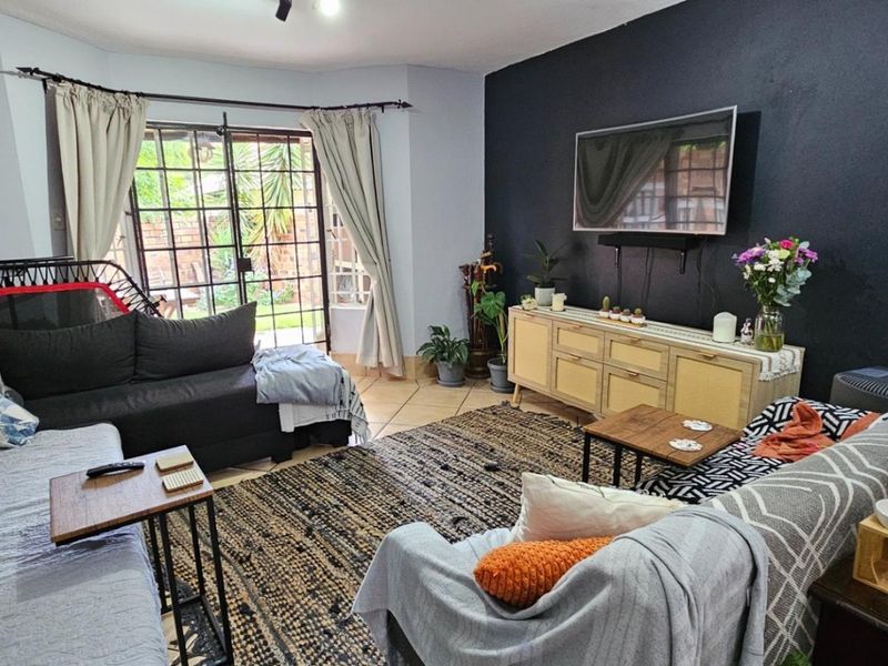 A comfortable living room featuring tiled flooring, a dark accent wall, and a sliding glass door providing access to the outdoor area.