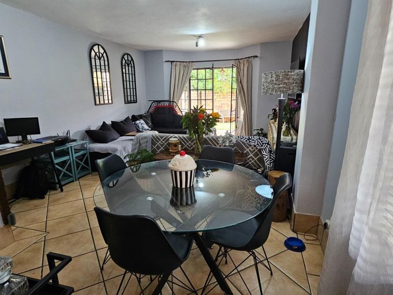 Open-plan living and dining area featuring tiled flooring and direct access to the outdoor patio through a sliding glass door.