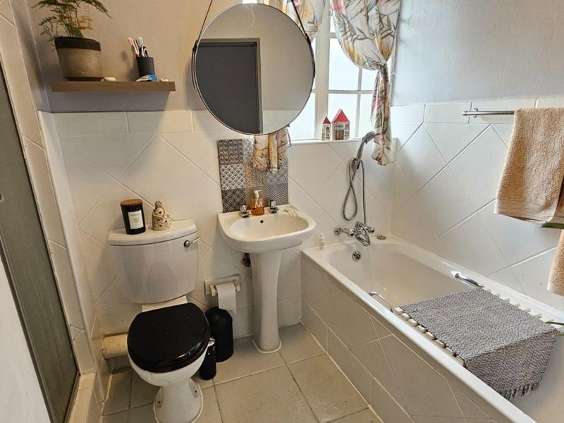 A functional bathroom featuring a pedestal basin, toilet, bathtub, and a separate shower enclosure with tiled finishes.