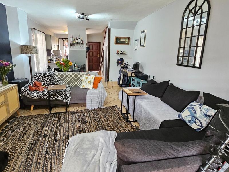 Open-plan living area featuring tiled flooring and neutral wall finishes, seamlessly connecting to the kitchen and entrance hallway.