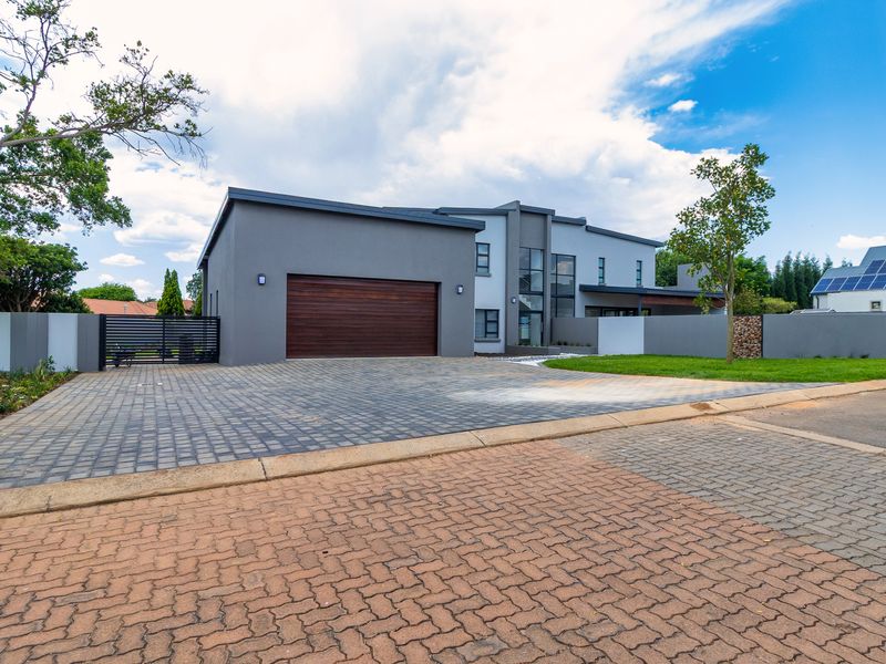 Modern double-story residence featuring a paved driveway, automated garage, and secure boundary walling in a well-maintained landscaped setting.