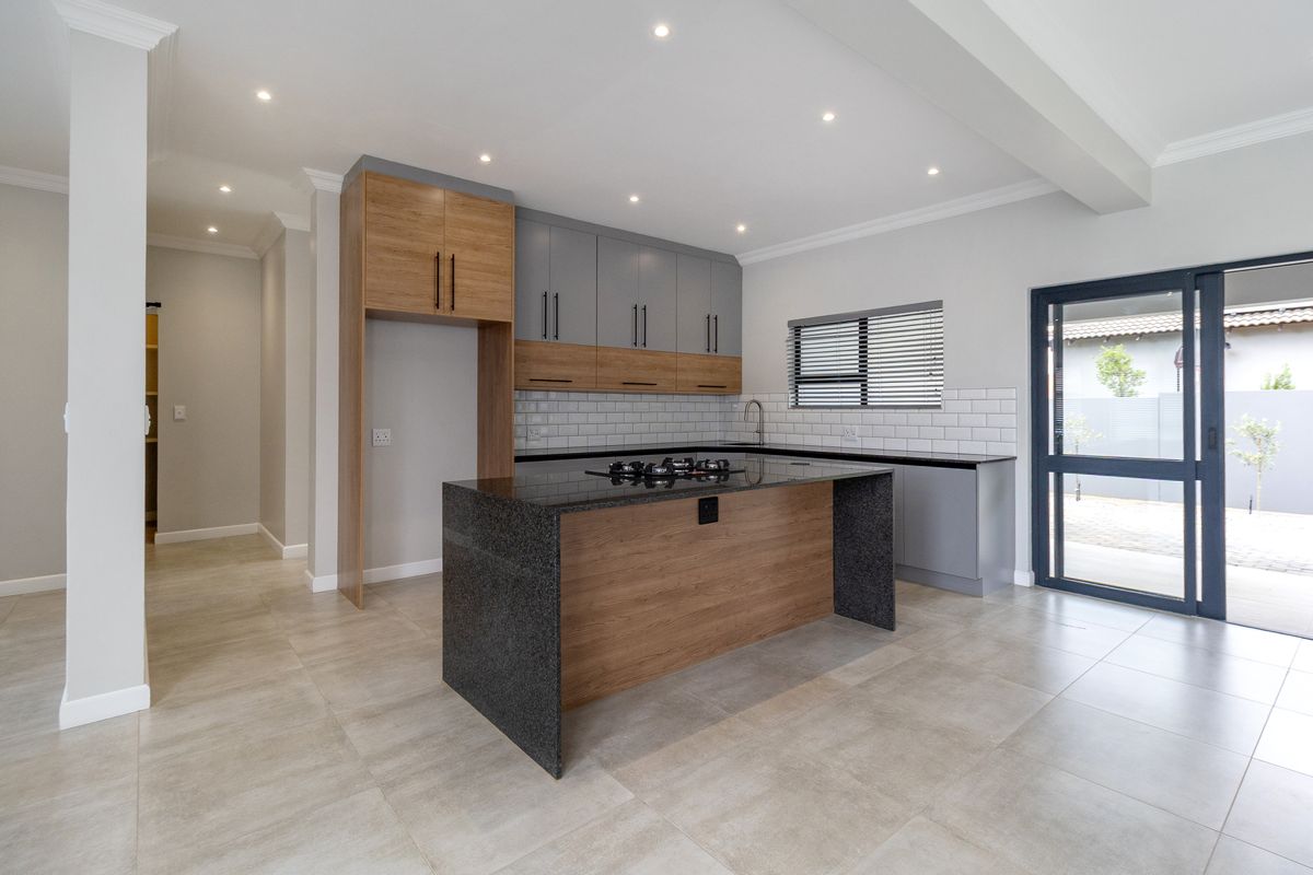 Modern kitchen featuring two-tone cabinetry, stone countertops, a central island with a gas hob, subway tile backsplash, and direct access to the outdoor area.