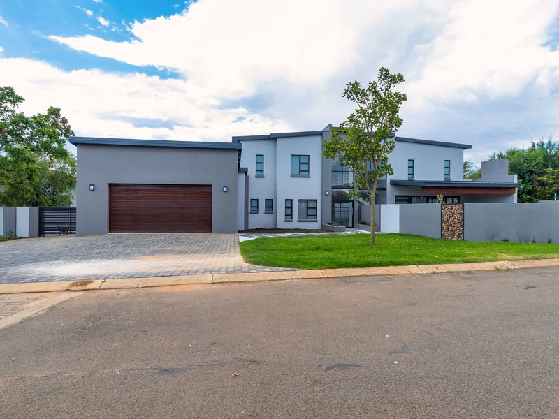 Modern double-story residential property featuring a paved driveway, timber garage door, and contemporary architectural facade with landscaped front garden.