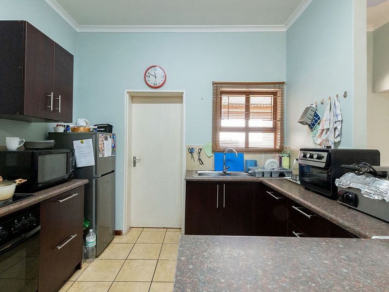 Functional kitchen featuring dark wood cabinetry, laminate countertops, tiled flooring, and a built-in oven, offering a practical layout for daily meal preparation.