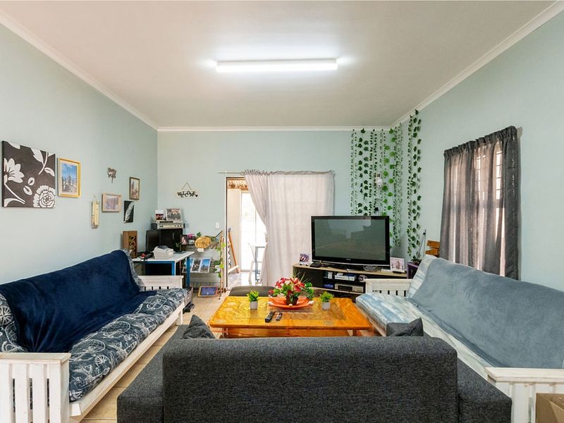 A functional living room featuring tiled flooring, cove cornicing, and a central fluorescent light fixture, providing a comfortable and practical living space.