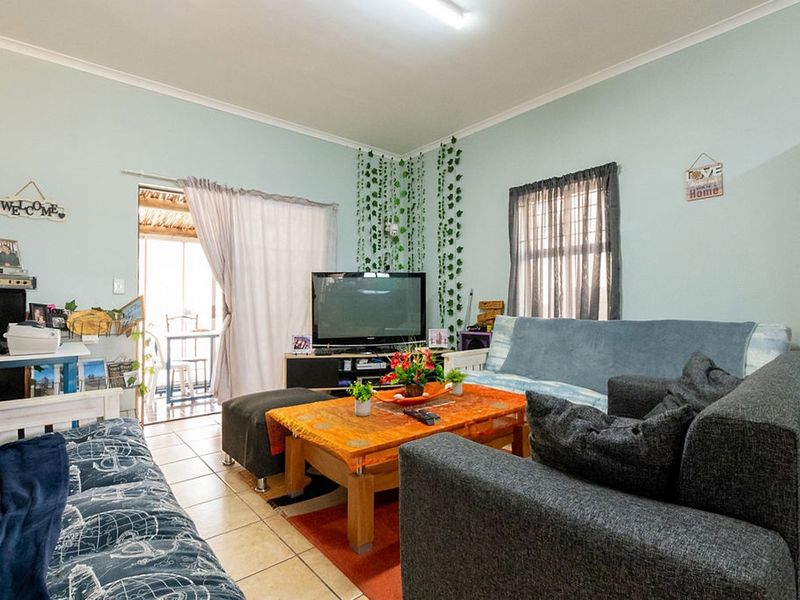 A functional living room featuring tiled flooring and a sliding glass door providing access to an outdoor area.