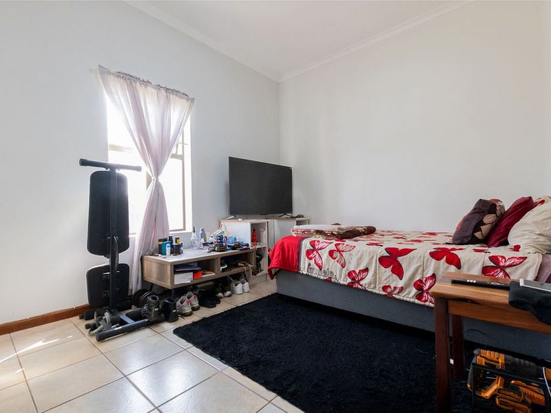 A functional bedroom featuring tiled flooring and a window, providing a neutral base for personalization.