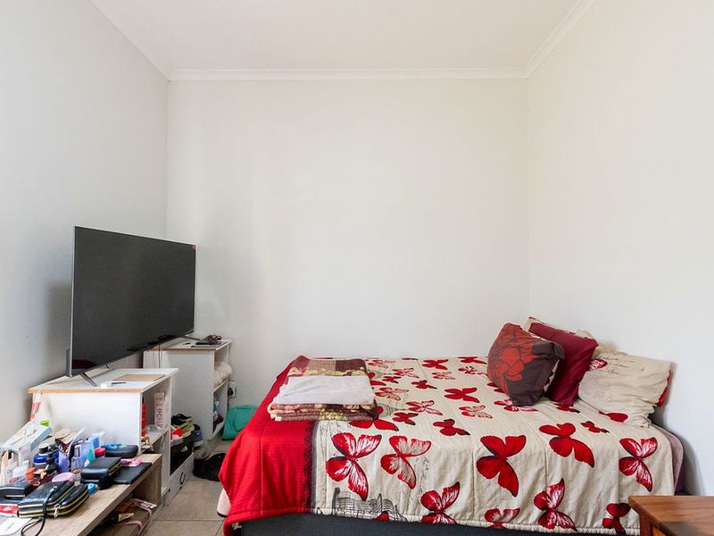 A standard bedroom featuring neutral walls and tiled flooring, providing a functional space for rest.