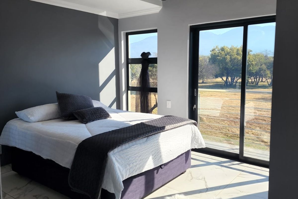 Modern bedroom featuring large format floor tiles, an exposed steel beam, and sliding glass doors providing scenic views and natural light.