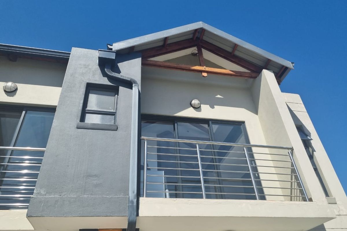 Modern exterior view of a residential balcony featuring stainless steel railings, sliding glass doors, and contemporary architectural finishes.