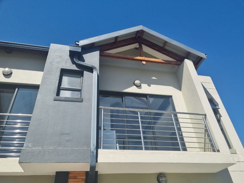 Modern exterior view of a residential balcony featuring stainless steel railings, sliding glass doors, and contemporary architectural finishes.