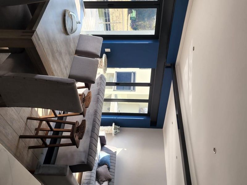 Modern open-plan living and dining area featuring large windows, recessed lighting, and contemporary finishes with a view of the exterior.