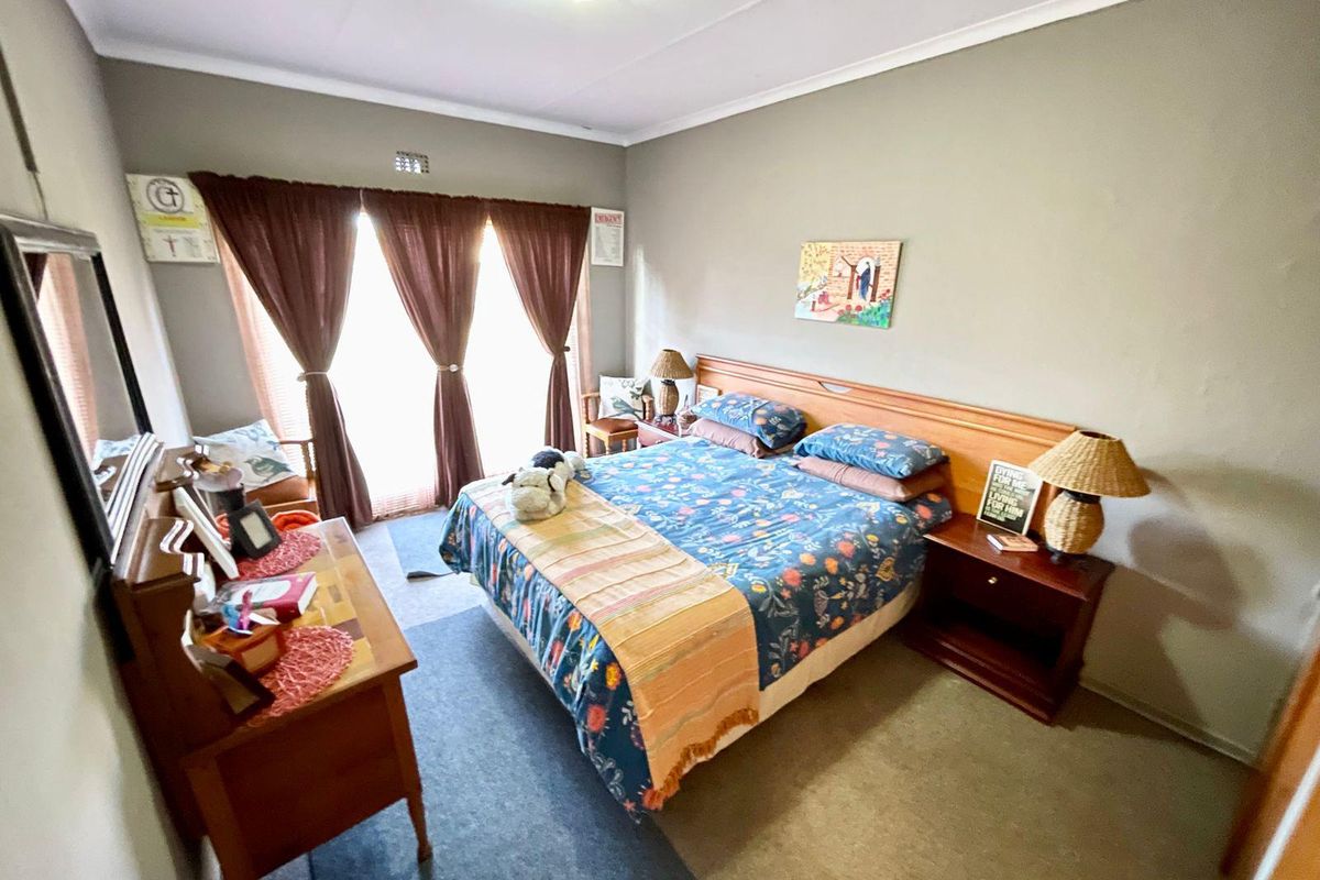A functional bedroom featuring a built-in headboard, carpeted flooring, and sliding glass doors providing access to the exterior.