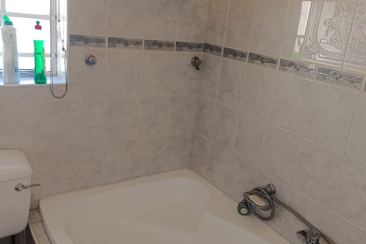 A functional bathroom featuring a built-in bathtub, toilet, and tiled walls. The space is ready for a modern update to enhance its aesthetic appeal.