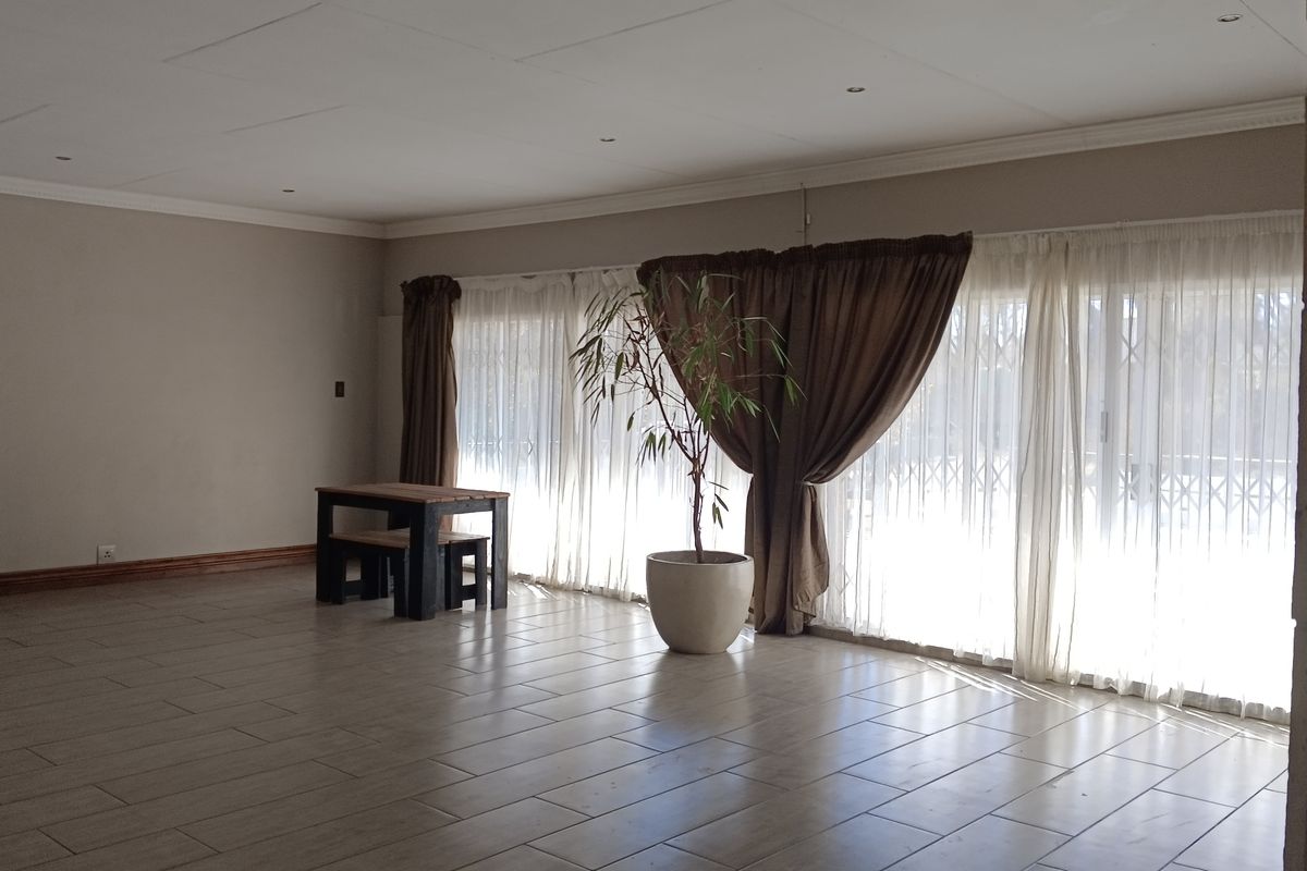 Spacious living area featuring neutral walls, tiled flooring, and large sliding glass doors that provide ample natural light and access to the outdoors.