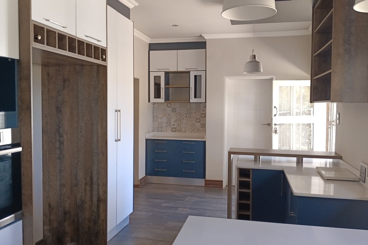 Modern kitchen featuring two-tone cabinetry, quartz countertops, built-in oven, decorative tiled backsplash, and integrated wine storage in a clean, contemporary layout.