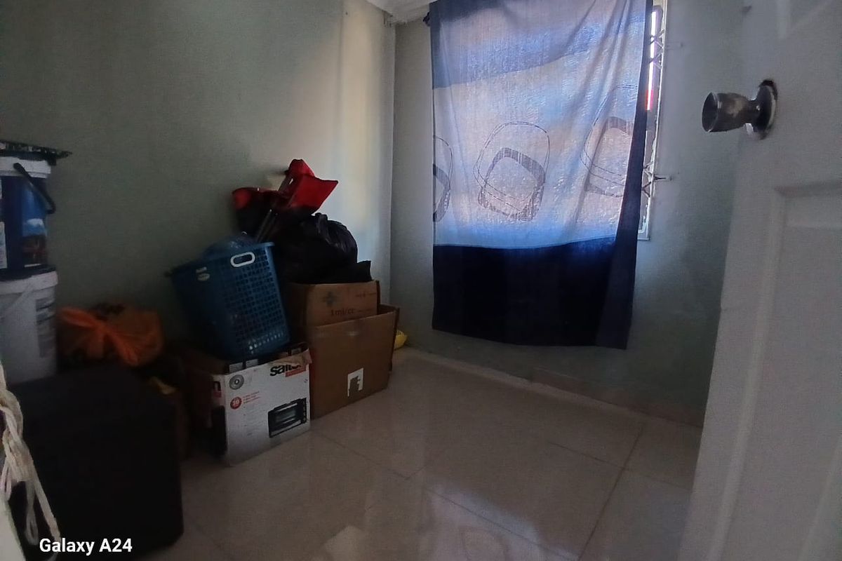 A small, empty bedroom featuring tiled flooring and a window with security bars, suitable for use as a guest room or home office.