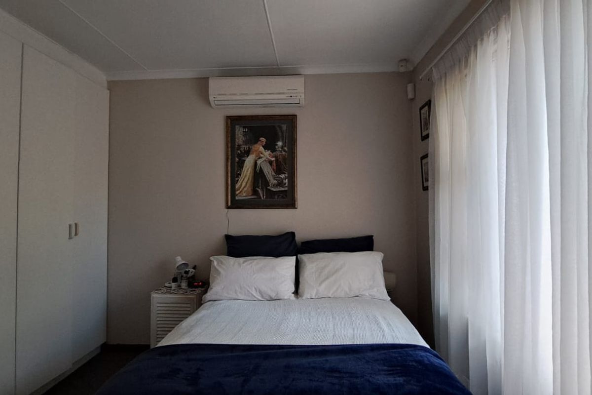 A functional bedroom featuring built-in cupboards and a wall-mounted split-system air conditioner for climate control.