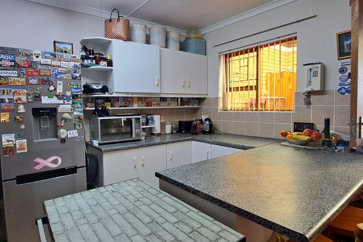 A functional kitchen featuring laminate countertops, tiled backsplash, and built-in cabinetry with a breakfast bar area.