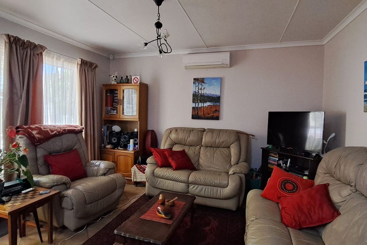 A comfortable living room featuring tiled flooring and a wall-mounted split-system air conditioner, providing a functional and climate-controlled space.