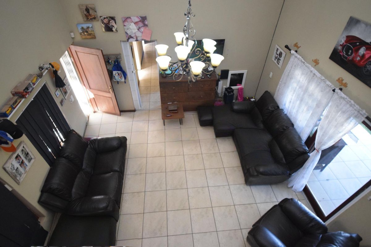 Spacious living room featuring high ceilings, tiled flooring, a central chandelier, and direct access to the outdoor area through sliding glass doors.