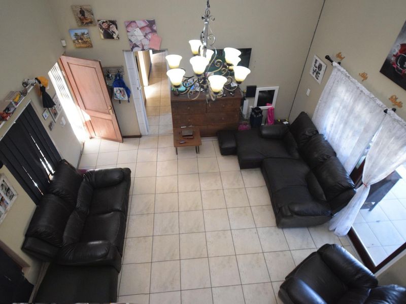 Spacious living room featuring high ceilings, tiled flooring, a central chandelier, and direct access to the outdoor area through sliding glass doors.