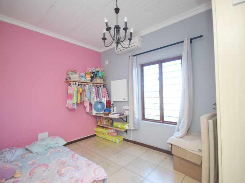 A bedroom featuring tiled flooring, a split-system air conditioner, and a chandelier, with a visible crack in the ceiling.