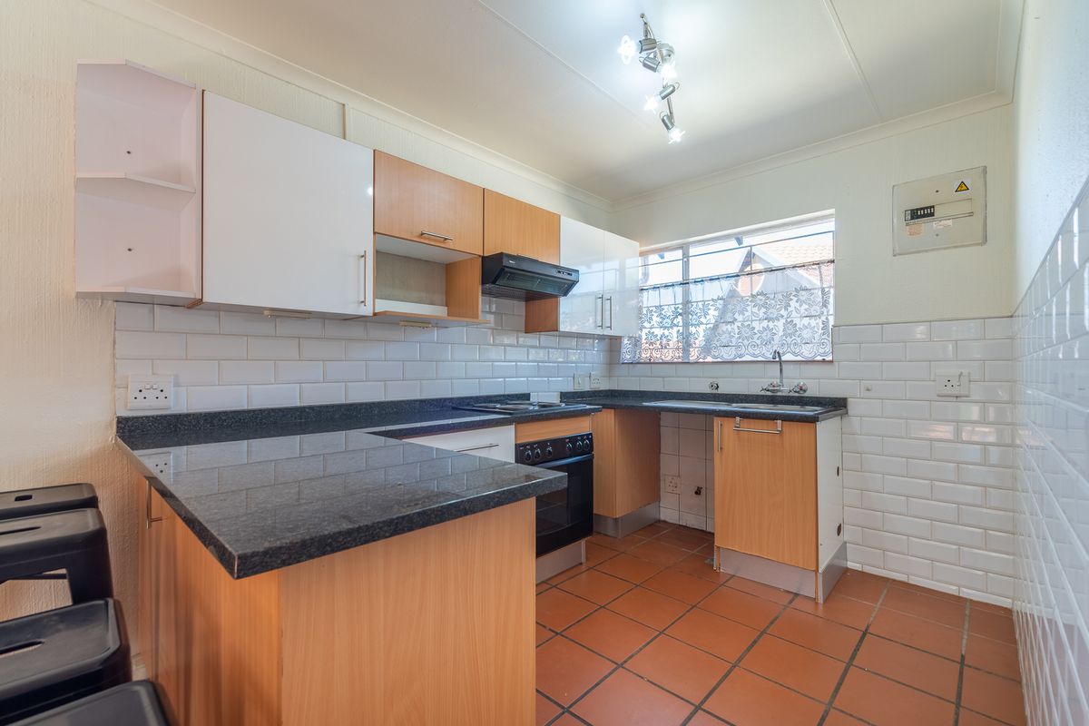 Functional kitchen featuring granite countertops, subway tile backsplash, built-in oven with extractor fan, and terracotta floor tiles.
