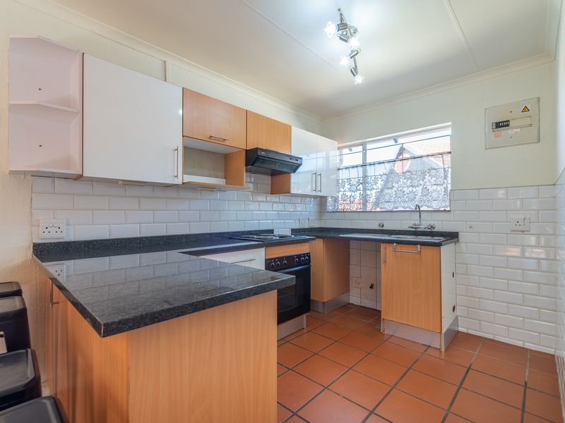 Functional kitchen featuring granite countertops, subway tile backsplash, built-in oven with extractor fan, and terracotta floor tiles.