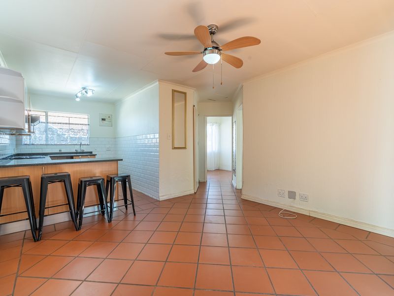 Open plan living and kitchen area featuring tiled flooring, a ceiling fan, and a functional kitchen with granite countertops and subway tile backsplash.